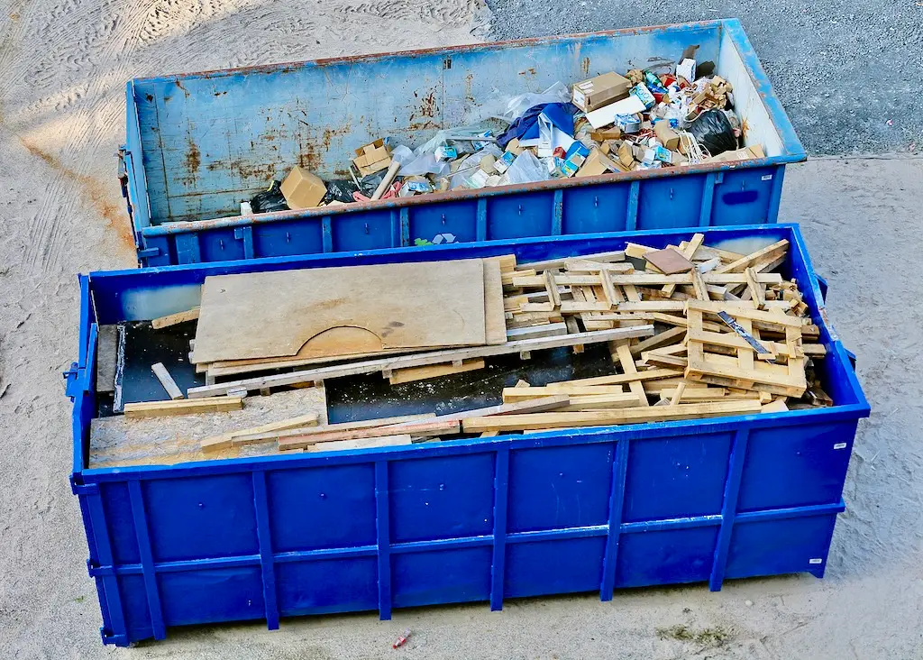 Blue construction dumpster filled with debris.