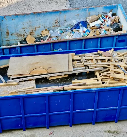 Blue construction dumpster filled with debris.